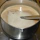 Step seven: Pour the mix into a saucepan. Add jaggery syrup. Add a pinch of salt. Pour about 3 1/2 small glasses of water into it.