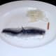 Unwrapped pickled herring or rollmop with dangerously protruding fin