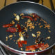 Step three: Throw in dry red chilies, tamarind, and garlic cloves. Saute for 30 seconds. Turn off the heat. Transfer the mixture to a plate.