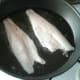 Sea bass fillets are added to hot frying pan