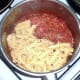 Pasta is added to spicy tomato sauce
