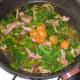 Tomato halves are added to kale and bacon