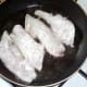 Floured whiting fillets are added to frying pan