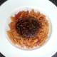 Ostrich burger is laid on spicy pasta bed