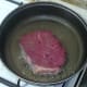 Seasoned steak is added to hot frying pan