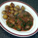 Chicken and spinach curry is plated with roast potatoes on the side