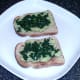 Spinach is scattered over guacamole on toast