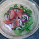 Watercress salad ingredients are seasoned and combined in a bowl
