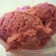 Two scoops of egg custard ice cream with red raspberries.