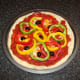 Mixed bell peppers and halved black olives are added to pizza