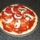 Tomato and mushroom are placed on top of the tomato sauce