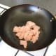 Dice the chicken and add it to a hot wok with sunflower oil.
