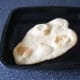 Naan bread removed from the oven, ready to be glazed with melted butter and served