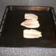 Sardine fillets are laid skin side down on an oiled grill pan and seasoned