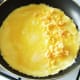 Cheese is scattered on half of duck egg omelette