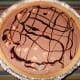 Drizzle the top of the softened ice cream with ribbons of chocolate and then alternate with caramel. The ribbons will begin to sink into different layers of the pie.