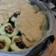 Apples covering toffee, cut sides up, filled with sultanas and walnuts. Flattened pieces of dough covering apples.