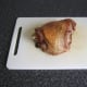 Turkey thigh is laid on chopping board for carving.