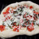 The pizza can be placed directly on the grill or on a pizza stone.