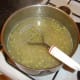A hand masher is used to crush the cooked potatoes and peas