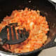 Sauteing and stirring the Mixture of Seasonings with the Onions.
