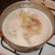 Ham pieces and whole navy beans are added to soup base