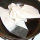 Wiping the excess oil and food remnants from the frying pan before frying the egg