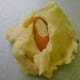 Topping each raw bit of cookie dough with a slivered almond.