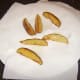 Deep fried potato wedges are drained on kitchen paper