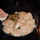 Layering cooked pierogi in baking dish.
