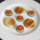 Toast circles are plated with tomato and cucumber