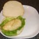 Chicken burger is laid on lettuce bed.