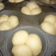 Butter the bottoms and sides of each of the cups in a 12 count muffin tin. Place three dough balls into each cup.