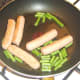 Green beans are added to fried sausages