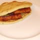 Second mini naan bread is laid on top of spicy sausages and beans