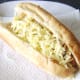 Grated cheese is scattered on hot dog for melting
