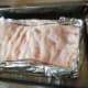 Aluminium foil is wrapped around the sides of the meat.