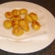 Deep fried potatoes are drained on kitchen paper.
