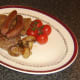 Tomatoes and mushrooms are plated with beef fry up components.