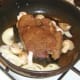 Onion and mushrooms are added to pan with part fried ox liver.