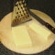 Wedge of cheddar cheese is cut for grating