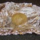 Skewered potato is laid in baking foil