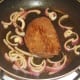 Ostrich steak is fried with red onion and garlic