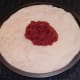 Tomato sauce is spooned on to pizza dough
