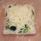 Cheese is carefully arranged over broccoli and bacon