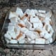 The cut-up bread squares are placed in a buttered baking pan.