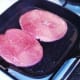 Oiled gammon steaks are added to hot griddle pan