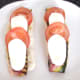 Mozzarella and tomato slices are laid alternately on pancetta