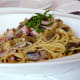 Pasta with bacon, shavings of Pecorino-Romano cheese, and basil