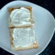 Cream cheese is spread on toast